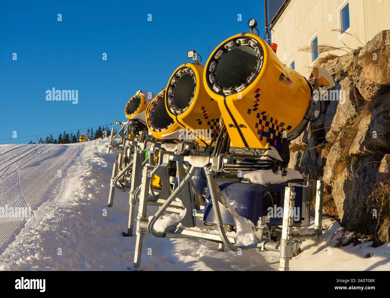 Cannoni da neve su una pista da sci nelle Alpi Foto Stock