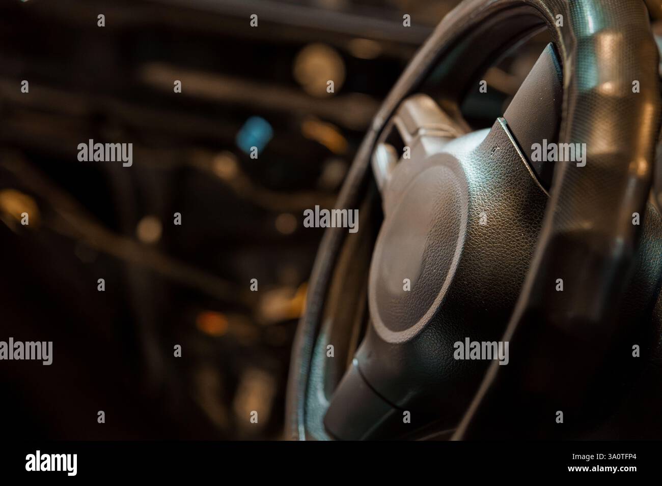 Vista ravvicinata del volante di un'auto in pelle nera in interni moderni. Foto Stock