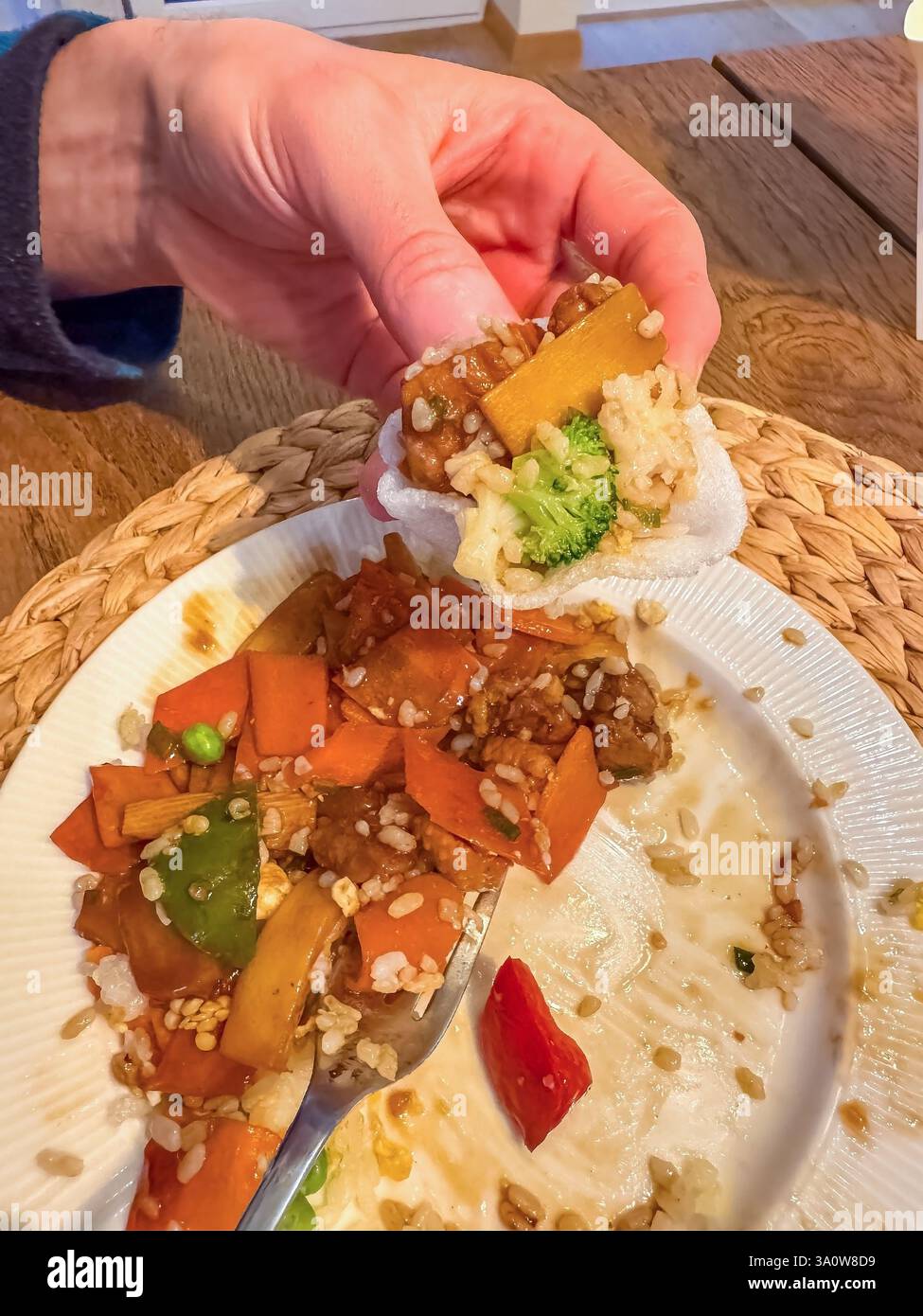 maschio che mangia in padella con verdure e riso, tenendo in mano una porzione piccola. Foto di alta qualità Foto Stock