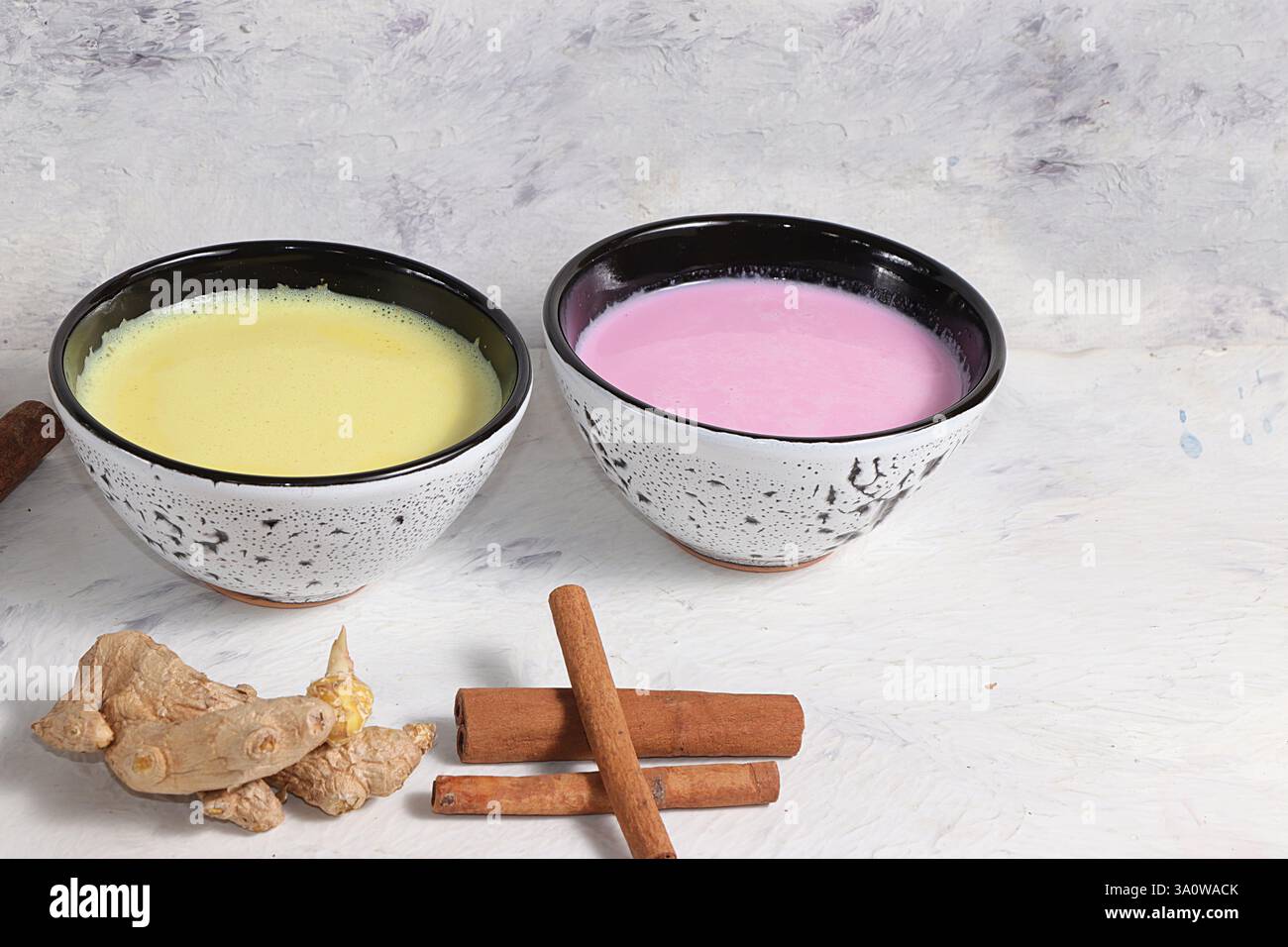 Latte alla curcuma e latte dorato rosa per dormire meglio, zenzero e cannella su un tavolo grigio, una bevanda alla moda e rilassante, ha proprietà antiossidanti, Foto Stock Latte alla curcuma e latte dorato rosa per dormire meglio, zenzero e cannella su un tavolo grigio, una bevanda alla moda e rilassante, ha proprietà antiossidanti, Foto Stock