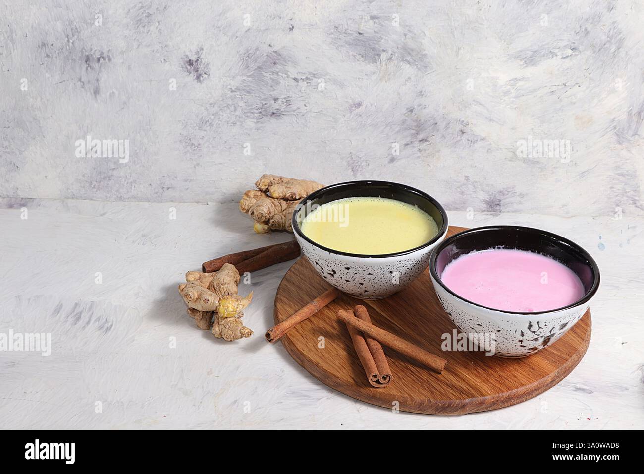 Latte alla curcuma e latte dorato rosa per dormire meglio, zenzero e cannella su un tavolo grigio, una bevanda alla moda e rilassante, ha proprietà antiossidanti, Foto Stock Latte alla curcuma e latte dorato rosa per dormire meglio, zenzero e cannella su un tavolo grigio, una bevanda alla moda e rilassante, ha proprietà antiossidanti, Foto Stock