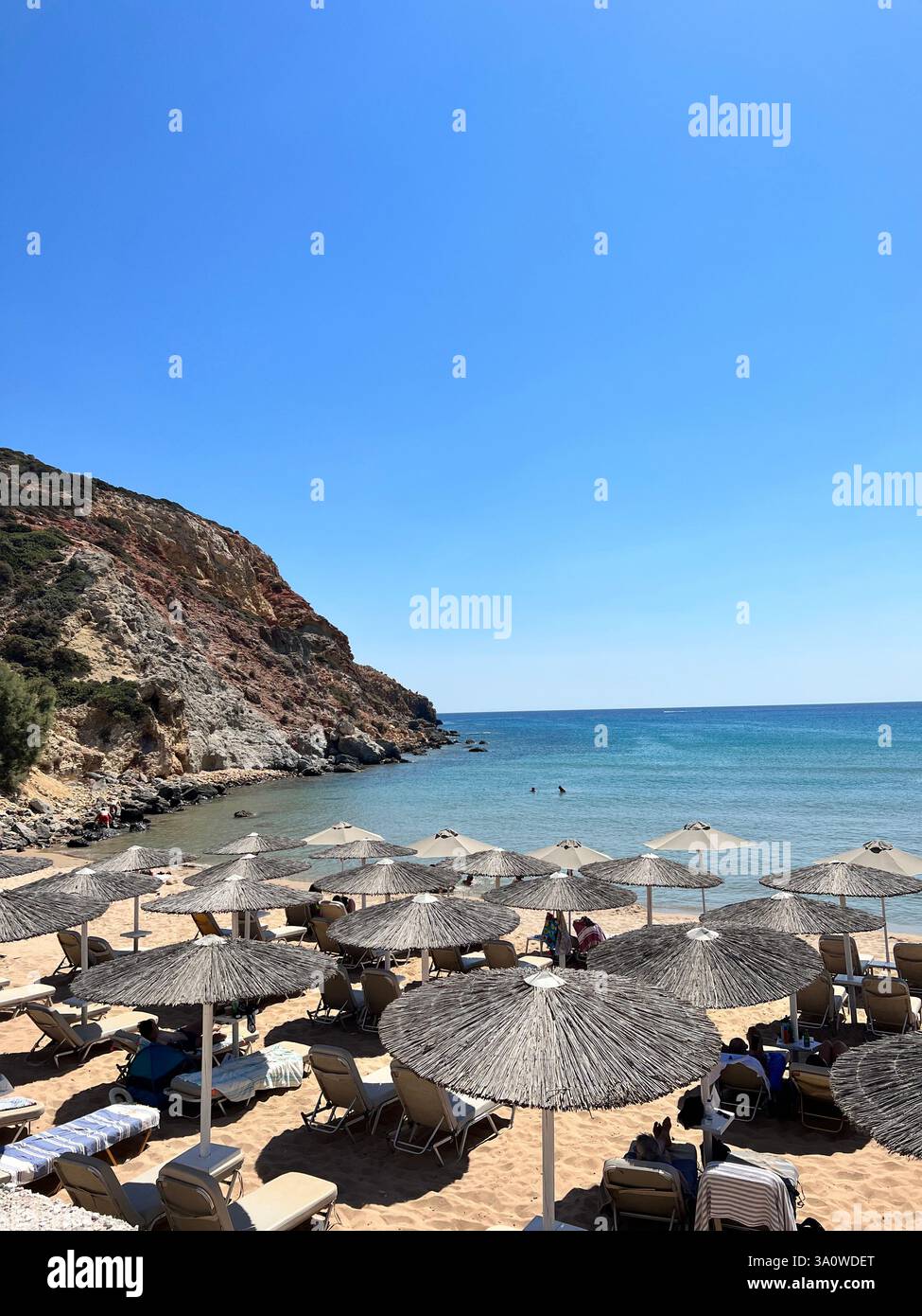 Spiaggia sabbiosa con ombrelloni di paglia, lettini e un mare turchese Foto Stock
