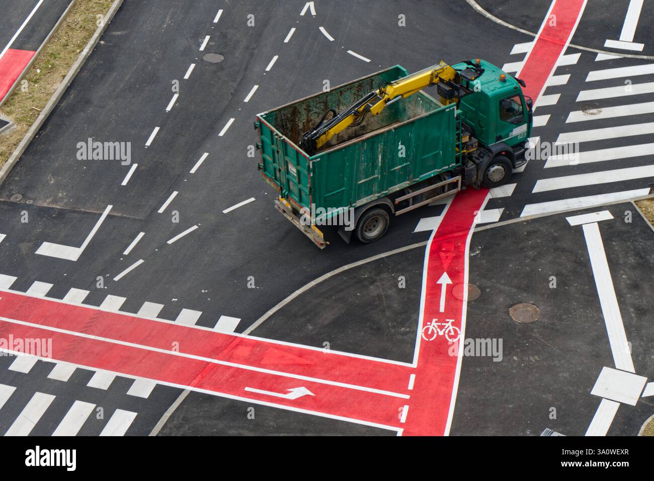 Un camion verde si trova all'incrocio stradale con piste ciclabili segnalate e percorsi pedonali. Foto Stock