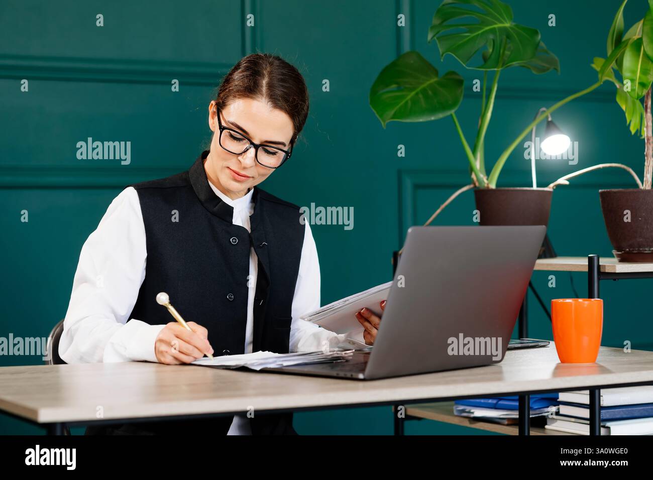 Donna d'affari che lavora nel suo ufficio moderno, rivede documenti o fatture che le vengono consegnate. Ideale per i temi del lavoro professionale, dell'efficienza dell'ufficio, Foto Stock