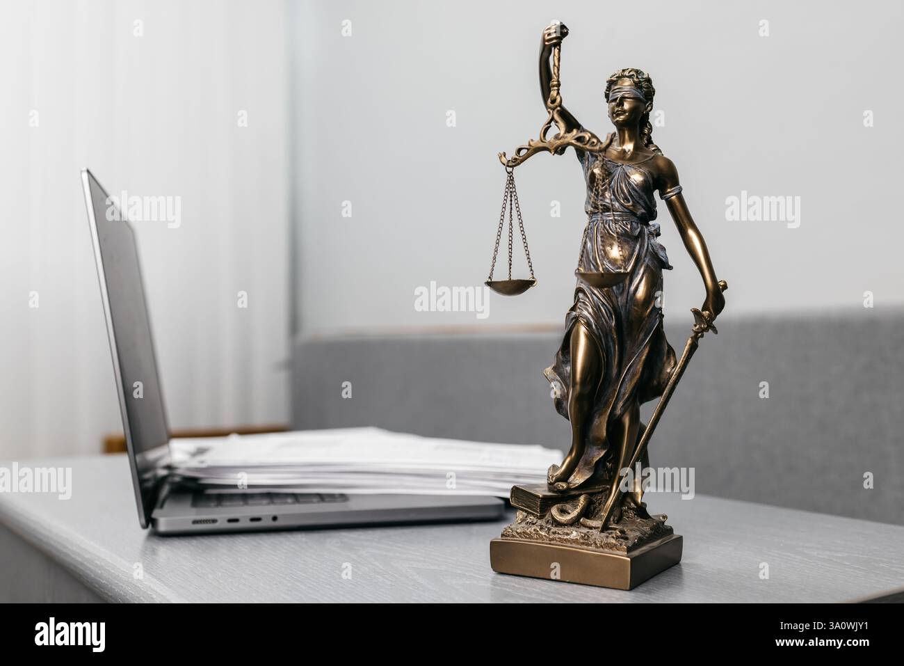 Una scrivania da avvocato con documenti contrattuali, un portatile e una statua della dea della giustizia. Un simbolo della legge, dei servizi legali e della giustizia Foto Stock