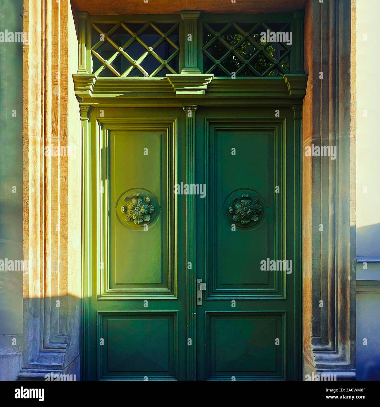 Una grande porta verde inondata dalla calda luce del sole, che proietta eleganti ombre sulla sua facciata storica. - Immagine stock catturata con smartphone