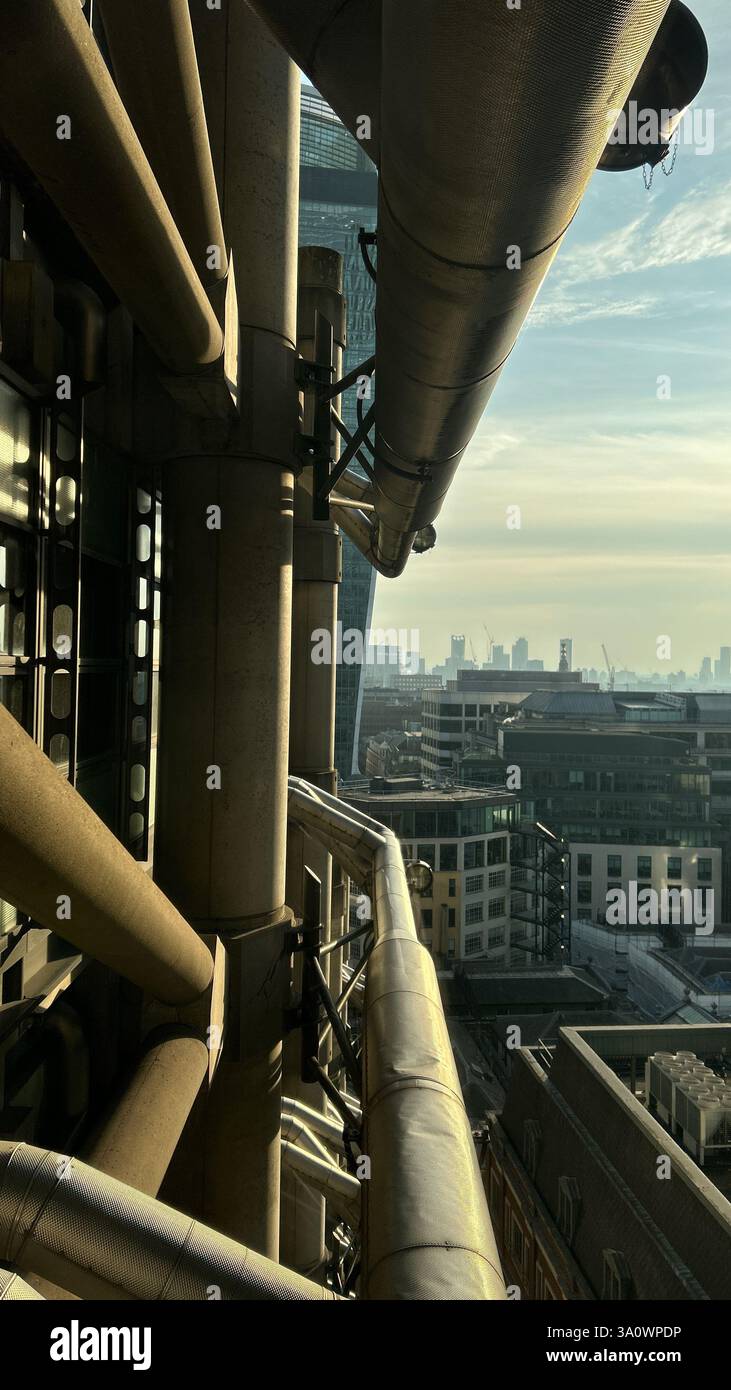 Vista laterale del Lloyd's Building (1 Lime Street) di Londra, scattata al tramonto, che mostra i condotti di ventilazione esterni tipici dell'architettura bowellista - Immagine stock catturata con smartphone
