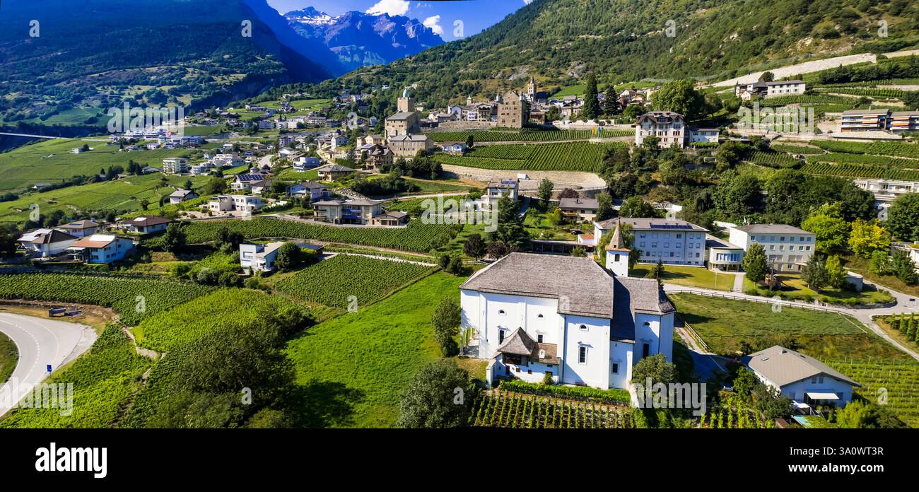 Viaggi in Svizzera, luoghi panoramici nel Canton Vallese. Città di Leuk circondata da vigneti e montagne alpine. Panorama aereo con droni e castelli medievali Foto Stock