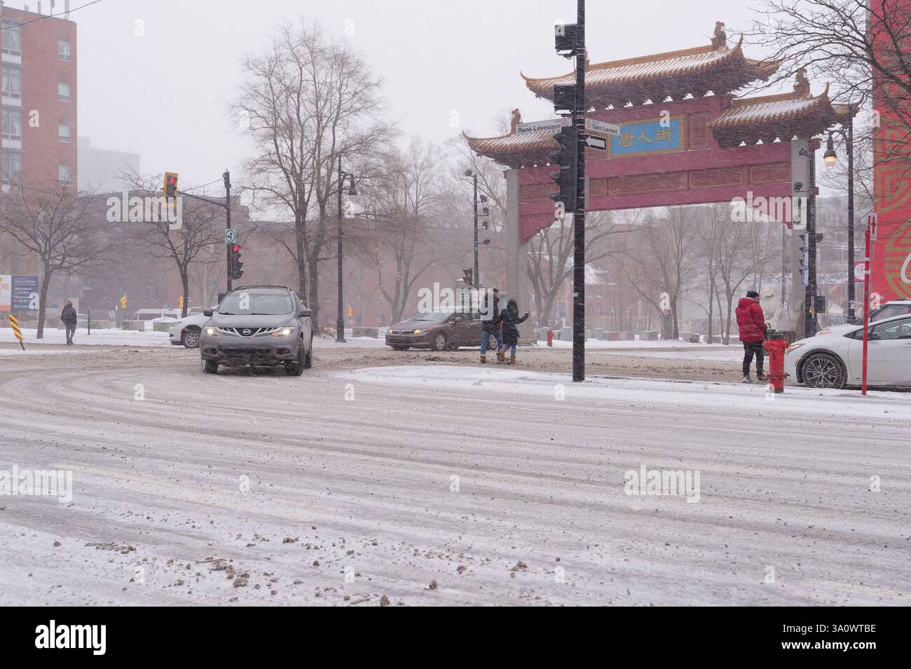 La neve cade sopra la Chinatown di Montreal, mentre pedoni e auto percorrono le strade invernali Foto Stock