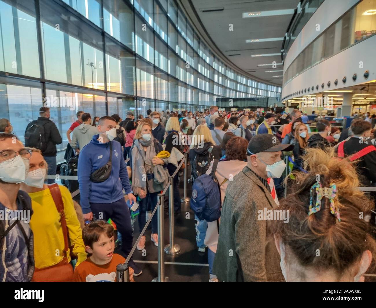 Folla di passeggeri / persone che indossano maschere facciali in coda all'aeroporto di Vienna; terminal dell'aeroporto affollato, code, tempi di attesa, file per il check-in - Immagine stock catturata con smartphone