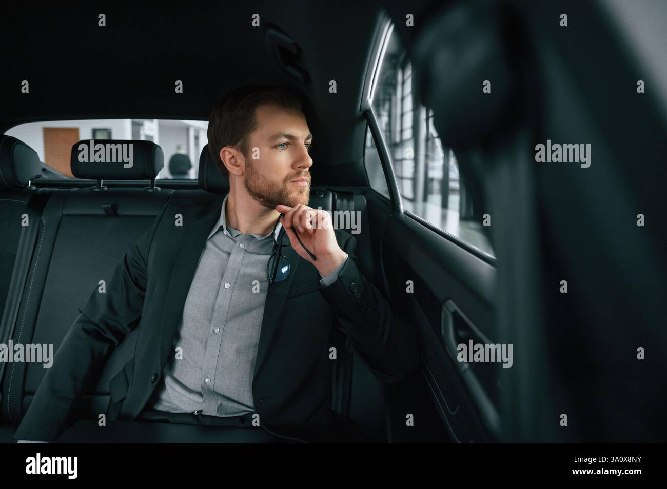 L'uomo in abiti da lavoro formali è seduto nell'automobile moderna. Foto Stock