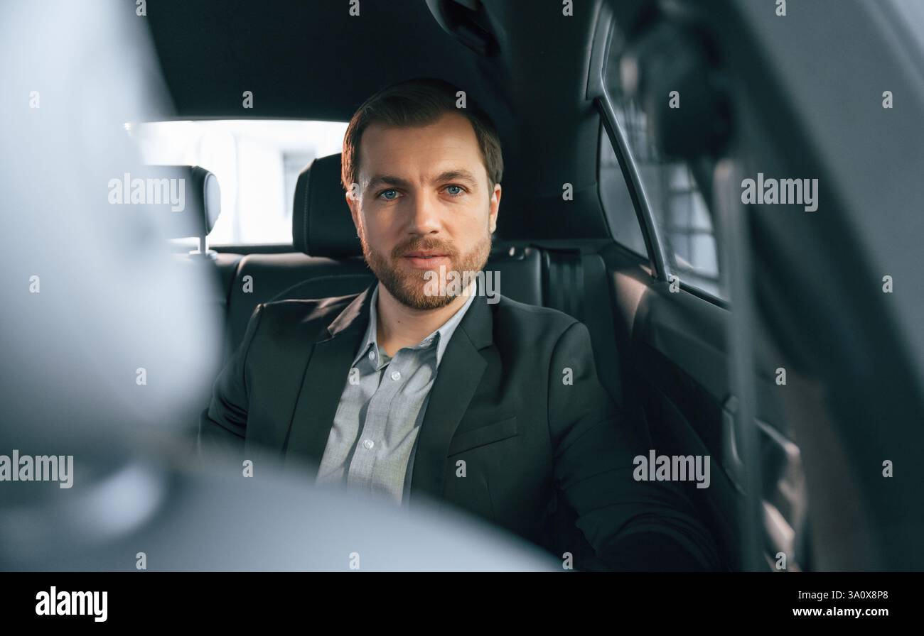 In un'automobile moderna e confortevole. Uomo in abiti da lavoro formali. Foto Stock