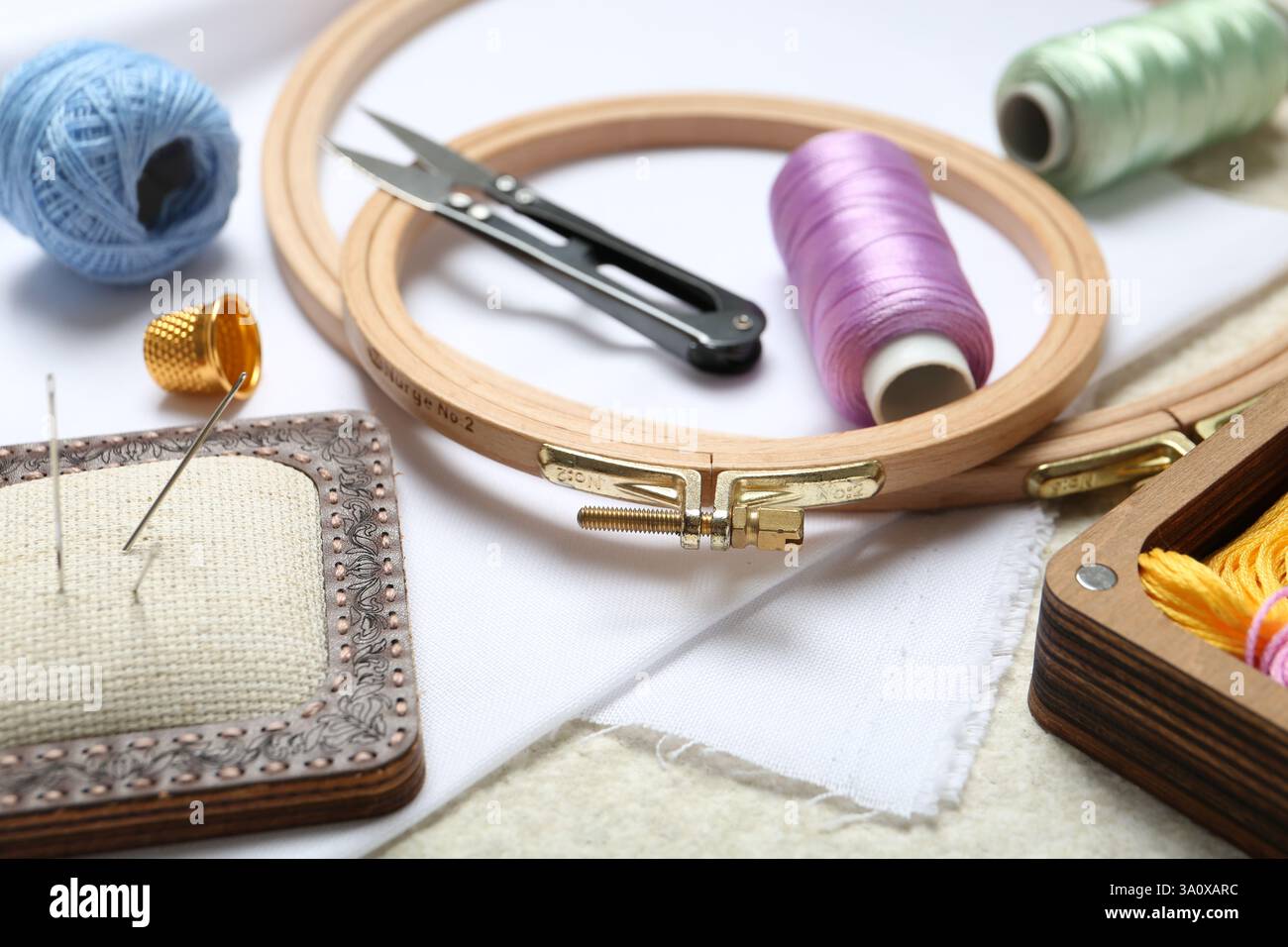 Ricamo. Diversi accessori per cucire su un tavolo con texture beige, primo piano Foto Stock