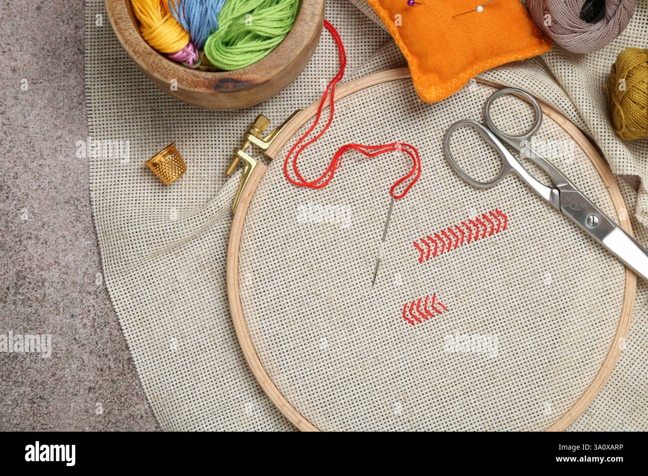 Ricami e diversi accessori per cucire su tavolo grigio, piatto Foto Stock