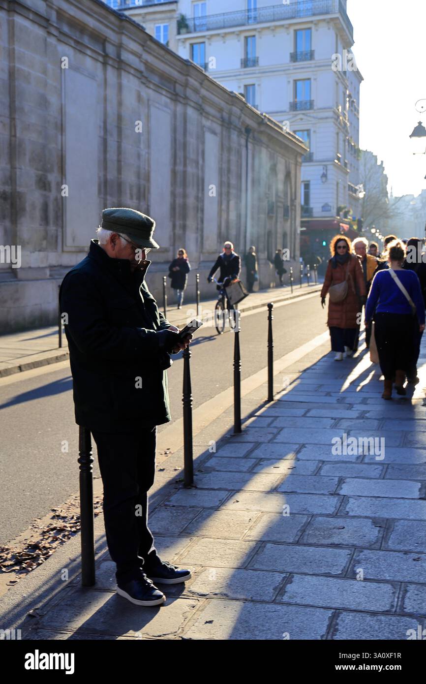 Un uomo appoggiato su un dissuasore che separa il marciapiede e la strada nel quartiere le Marais. Parigi. Francia Foto Stock