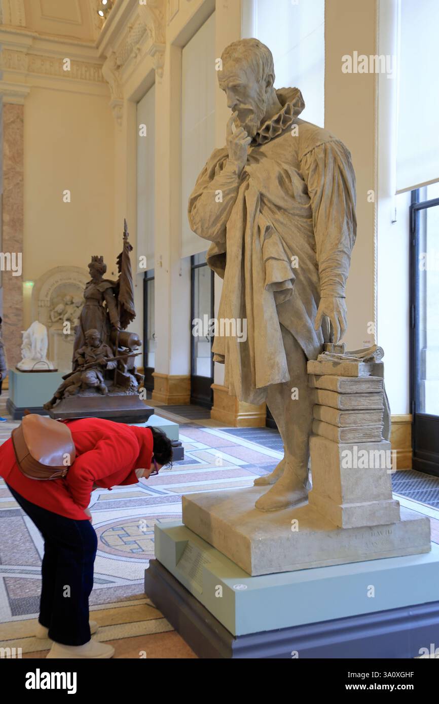 Una visitatrice femminile che legge i titoli della scultura di Ambroise Pare 1839 dello scultore francese Pierre-Jean David, alias David d'Angers, esposta nel Petit Palais.Paris.France Foto Stock