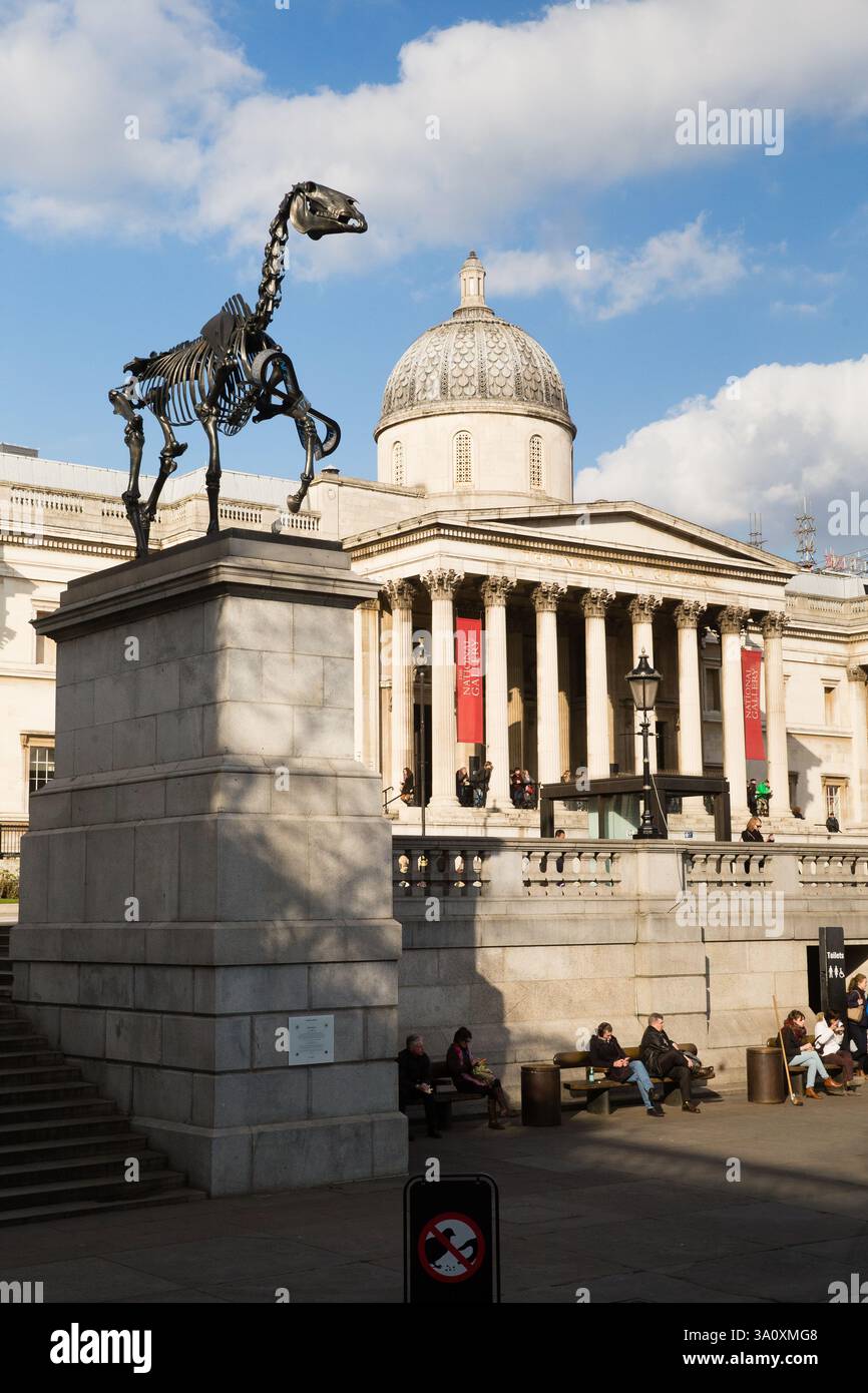 Scultura in metallo dello scheletro di cavallo alla National Gallery di Londra. Le persone si rilassano vicino al punto di riferimento. Foto Stock
