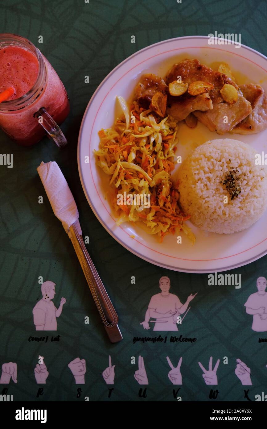 Pranzo a base di pollo alla griglia con frullato di riso e anguria sul tavolo con le figure del linguaggio dei segni al Cafe de la Sonrisas (caffè sorridente), dove i lavoratori sono sordi-muti e disabili nel centro storico di Granada. Nicaragua Foto Stock