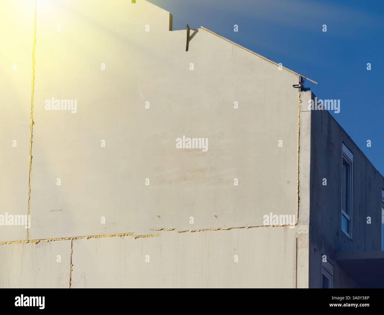 Ombre angolari e forme geometriche dominano la facciata di un edificio modernista, sotto un cielo azzurro. Foto Stock