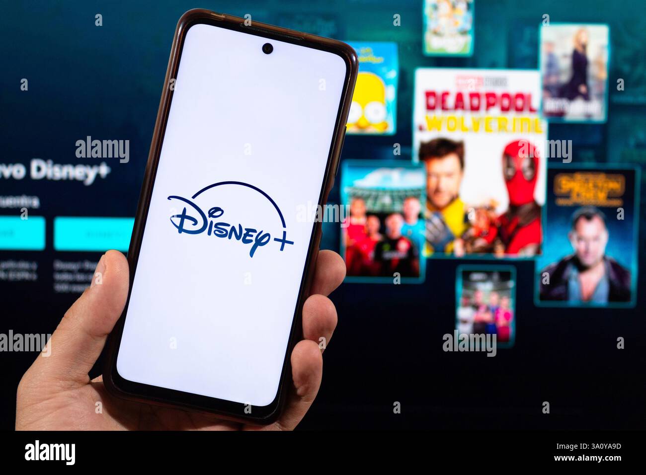 BOGOTÀ, COLOMBIA - 5 MARZO 2025 Una mano maschile che tiene in mano uno smartphone Disney e il logo dell'app in streaming in bianco e sfocato sullo sfondo Foto Stock
