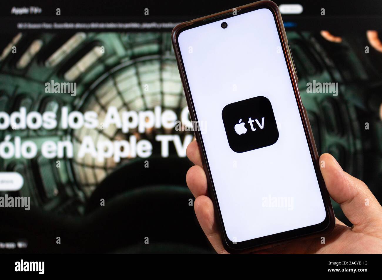 BOGOTÀ, COLOMBIA - 5 MARZO 2025 primo piano di una mano che regge uno smartphone con il simbolo Apple TV e l'interfaccia Apple tv sfocata sullo sfondo Foto Stock