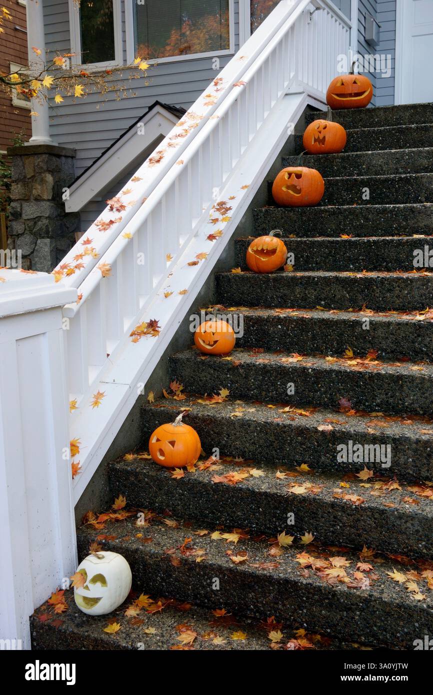 Zucche di Halloween scolpite che riposano sui gradini anteriori di una casa Foto Stock