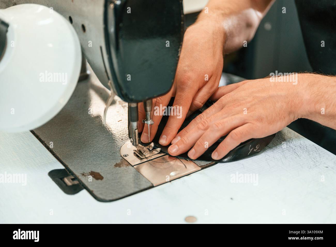 Processo di cucitura. Vista ravvicinata. Le mani dell'uomo sul tavolo, usando una macchina fissa. Foto Stock