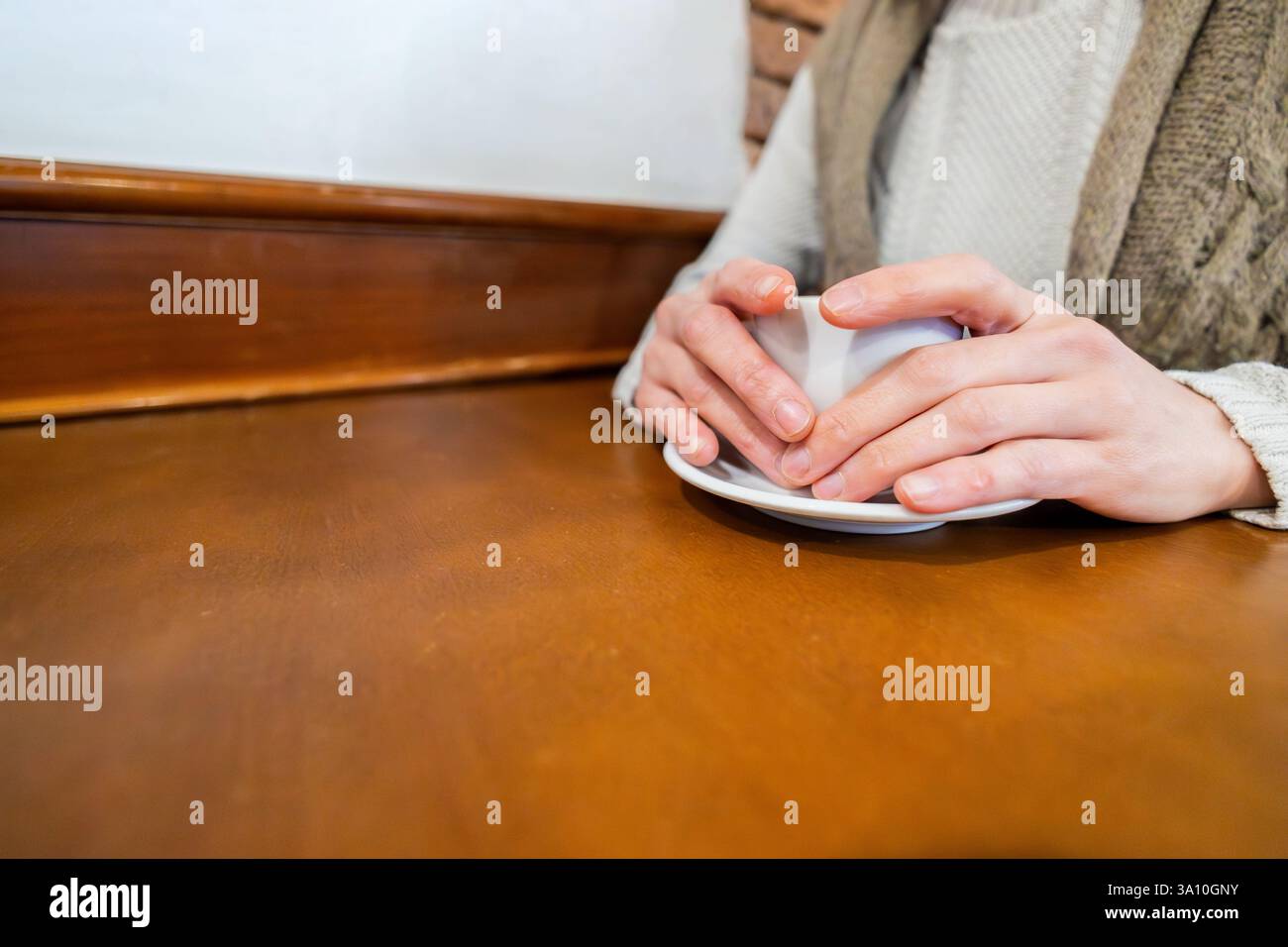 Mani che tengono una tazza di caffè caldo in un caffè rustico. Stile di vita, bevete. Foto Stock