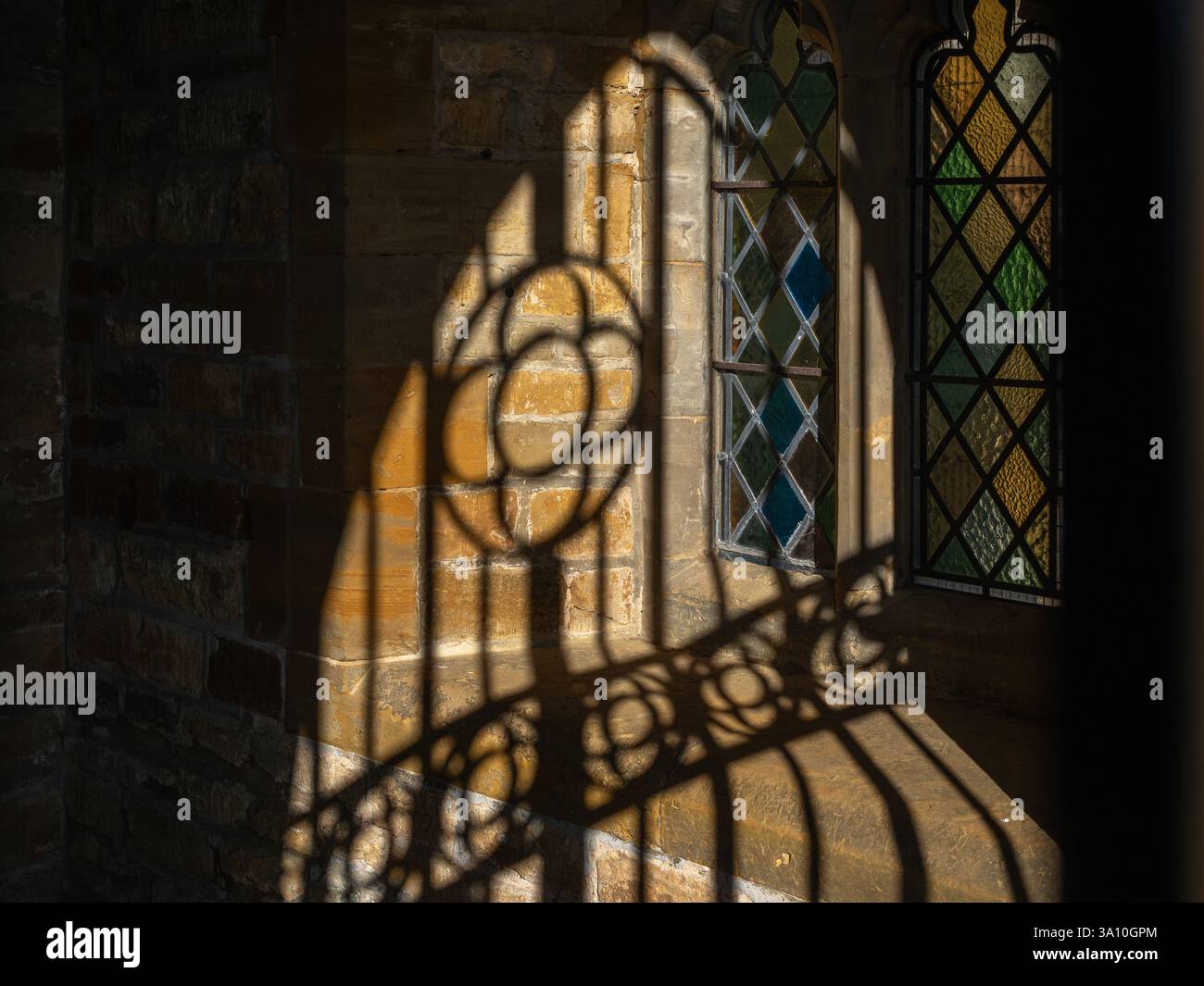 Ombre dure da un cancello metallico all'interno di un portico della chiesa, chiesa della Santa Croce, villaggio di Milton Malsor, Northamptonshire, Regno Unito Foto Stock