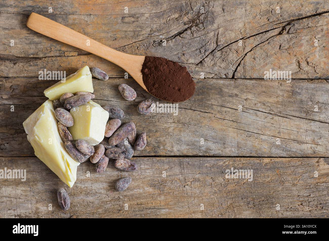 Burro di cacao o olio solido di cacao con cacao in polvere nel cucchiaio e fagioli di cacao crudi in ciotola di legno sullo sfondo rustico, olio naturale sano Foto Stock