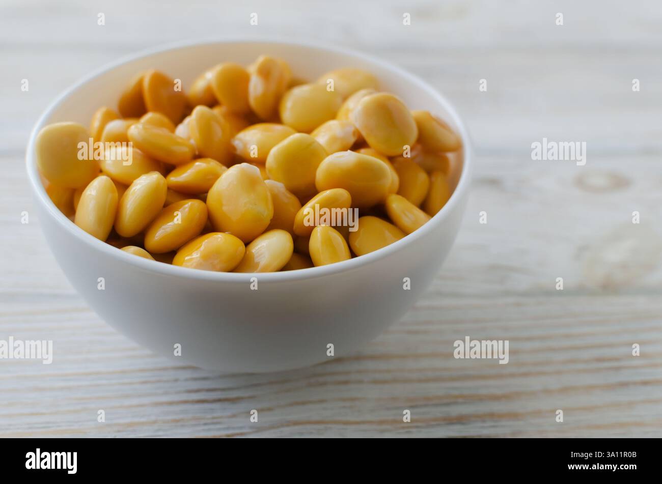 Fagioli Lupin in una ciotola bianca su un tavolo di legno. Cucina italiana. Tipo di legumi. Concetto di cibo sano. Orientamento orizzontale. Messa a fuoco selettiva. Copia spac Foto Stock