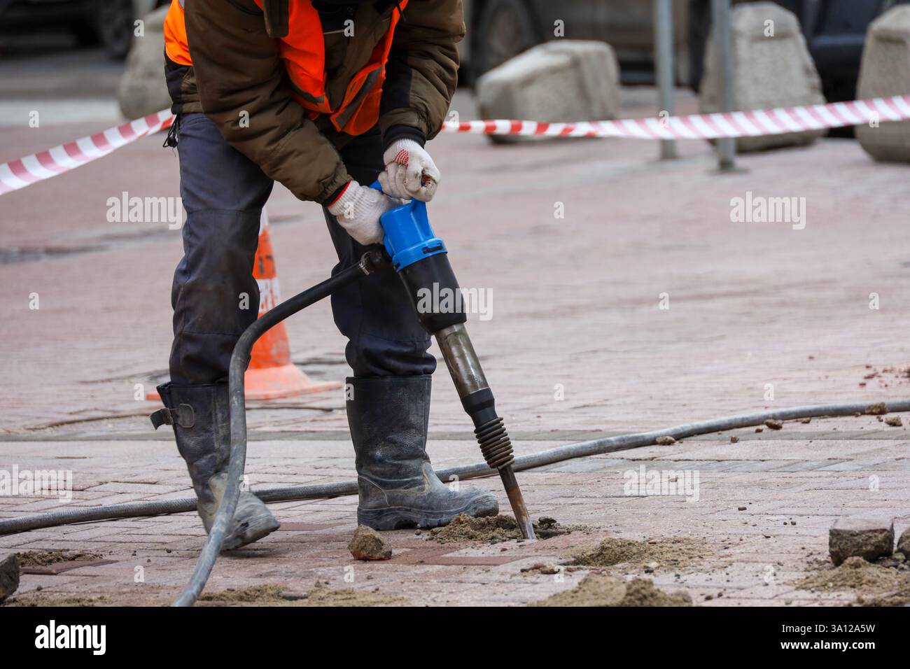 L'operatore ripara la superficie stradale con un martello. Lavori di costruzione, posa di lastre di pavimentazione in città Foto Stock