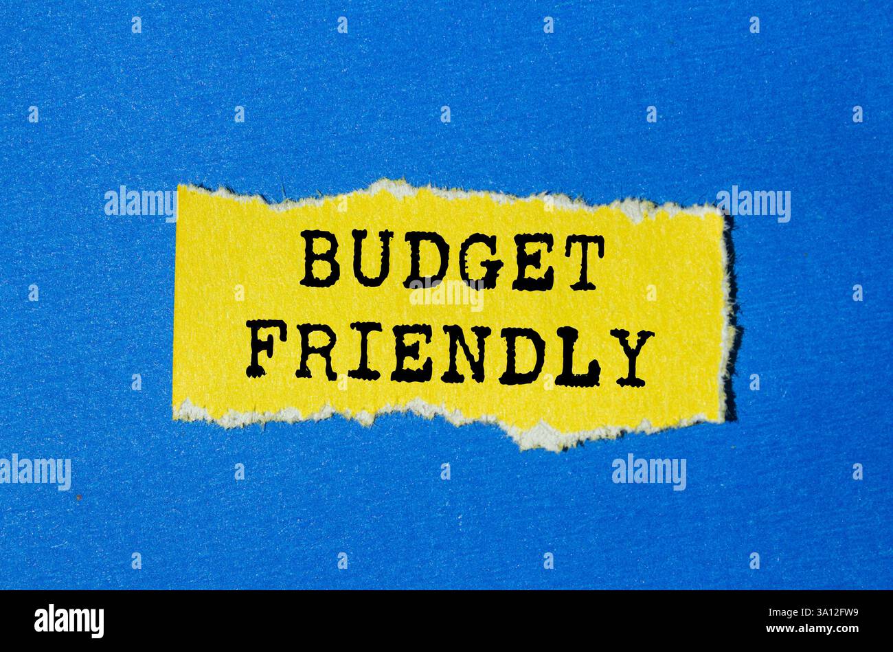 Messaggio economico scritto su un foglio giallo strappato su sfondo blu. Simbolo di budget concettuale. Copia spazio. Foto Stock