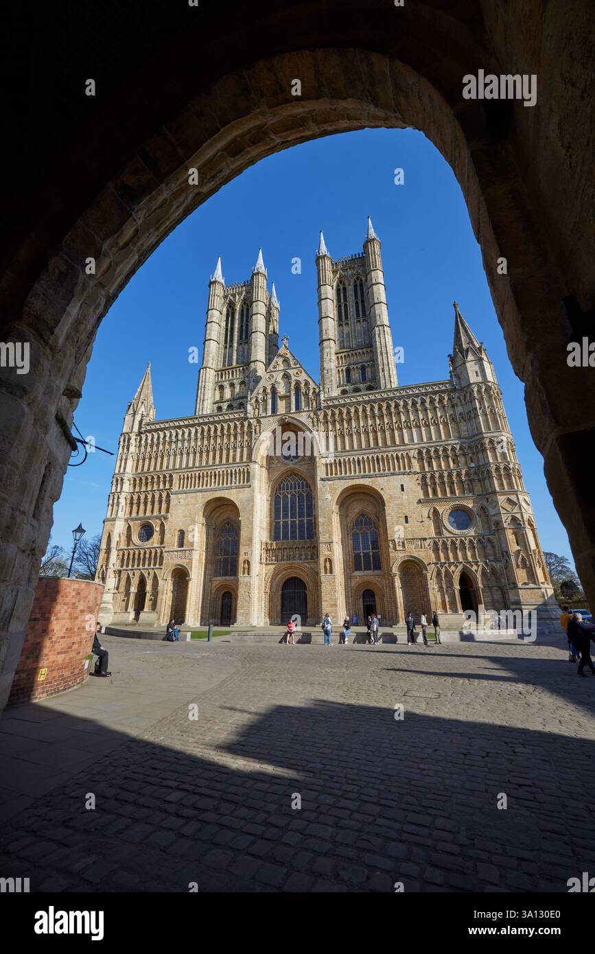 Il fronte occidentale della cattedrale di Lincoln è una grandiosa facciata medievale caratterizzata da un'intricata architettura gotica, guglie torreggianti e grandi porte ad arco. Foto Stock