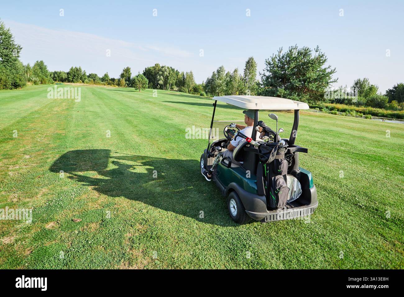 Un golfista con una gamba protesica pratica il proprio swing in una bella giornata di sole, utilizzando un golf cart adattivo per il supporto e la mobilità. Foto Stock