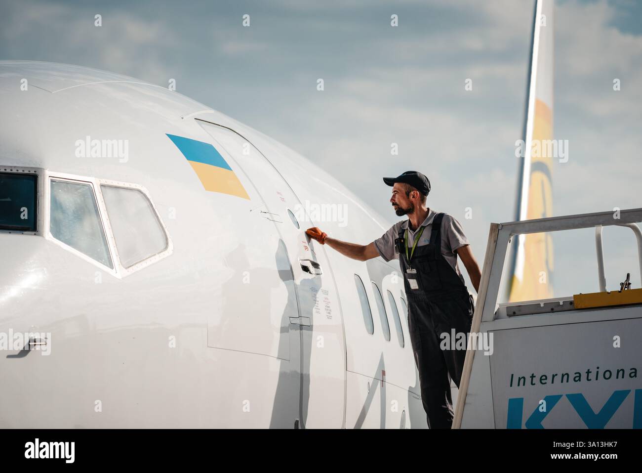 L'equipaggio di terra dell'aeroporto bussava alla porta dell'aereo. Foto all'aperto di un uomo in piedi sulle scale d'imbarco e che bussa alla porta dell'aereo. Foto Stock