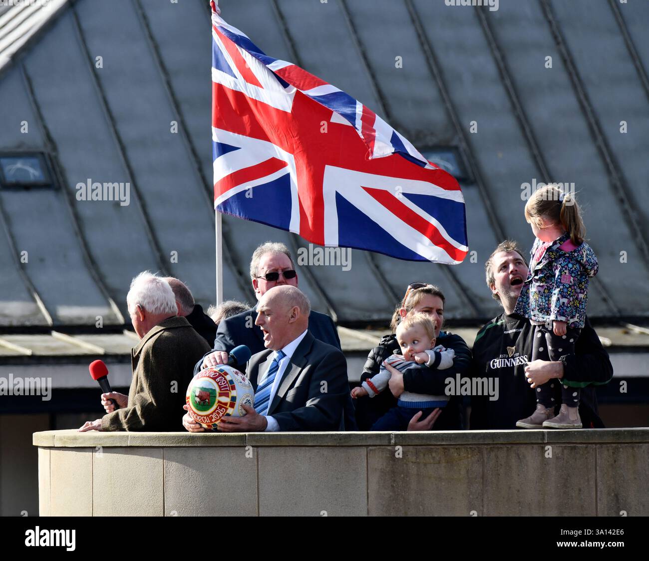 Ashbourne Royal Shrovetide, antica partita di baseball con il contadino locale David Bott che alza il pallone sul basamento del centro città. Foto Stock