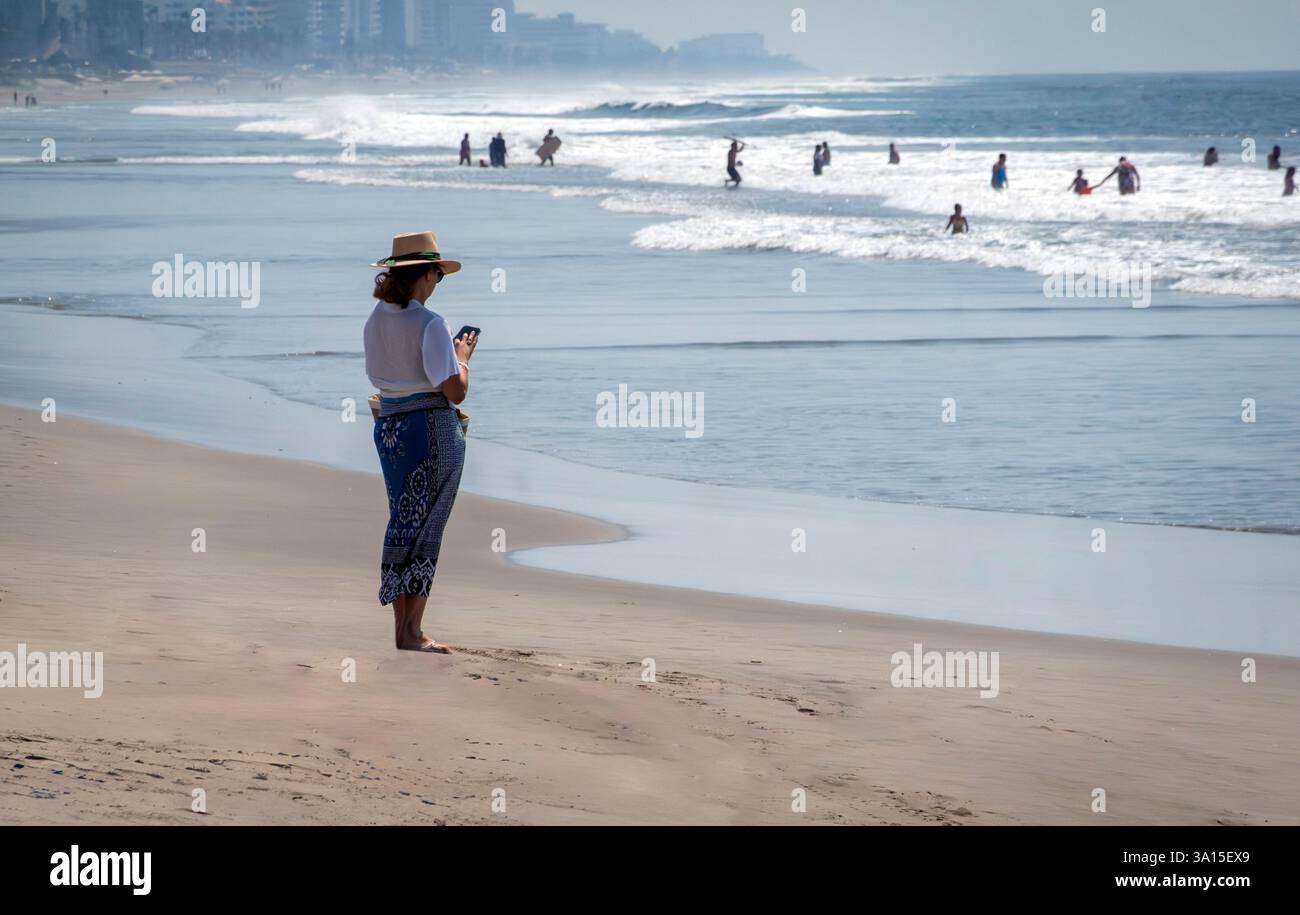 Donna con il telefono su una spiaggia Foto Stock