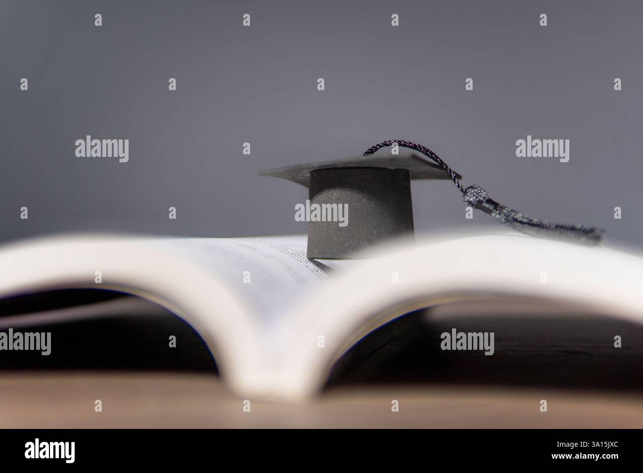 Un piccolo cappuccio graduato poggia su un libro aperto. Istruzione, realizzazione e concetto di conoscenza. Foto Stock