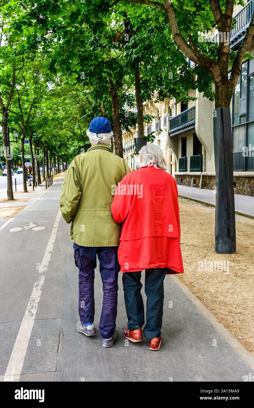 Coppia anziana che cammina braccio in braccio lungo il viale alberato - Parigi, Francia. Foto Stock