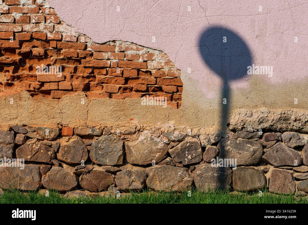 Contrasto urbano - ombra posta sul muro di mattoni danneggiato Foto Stock