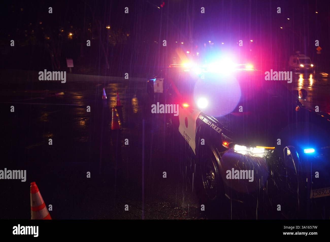 La polizia coordina il traffico in un tratto allagato della strada. San Diego ha subito una forte pioggia che ha portato a significative inondazioni in tutta la città. Nell'area di la Jolla, almeno quattro auto sono sommerse con livelli d'acqua quasi interamente coperti. Contemporaneamente, diversi incidenti automobilistici si sono verificati durante la tempesta, provocando risposte dal dipartimento di polizia di San Diego. Le autorità hanno chiuso le strade allagate per garantire la sicurezza pubblica, mentre il National Weather Service ha emesso un avviso di inondazione per alcune zone di San Diego. Foto Stock