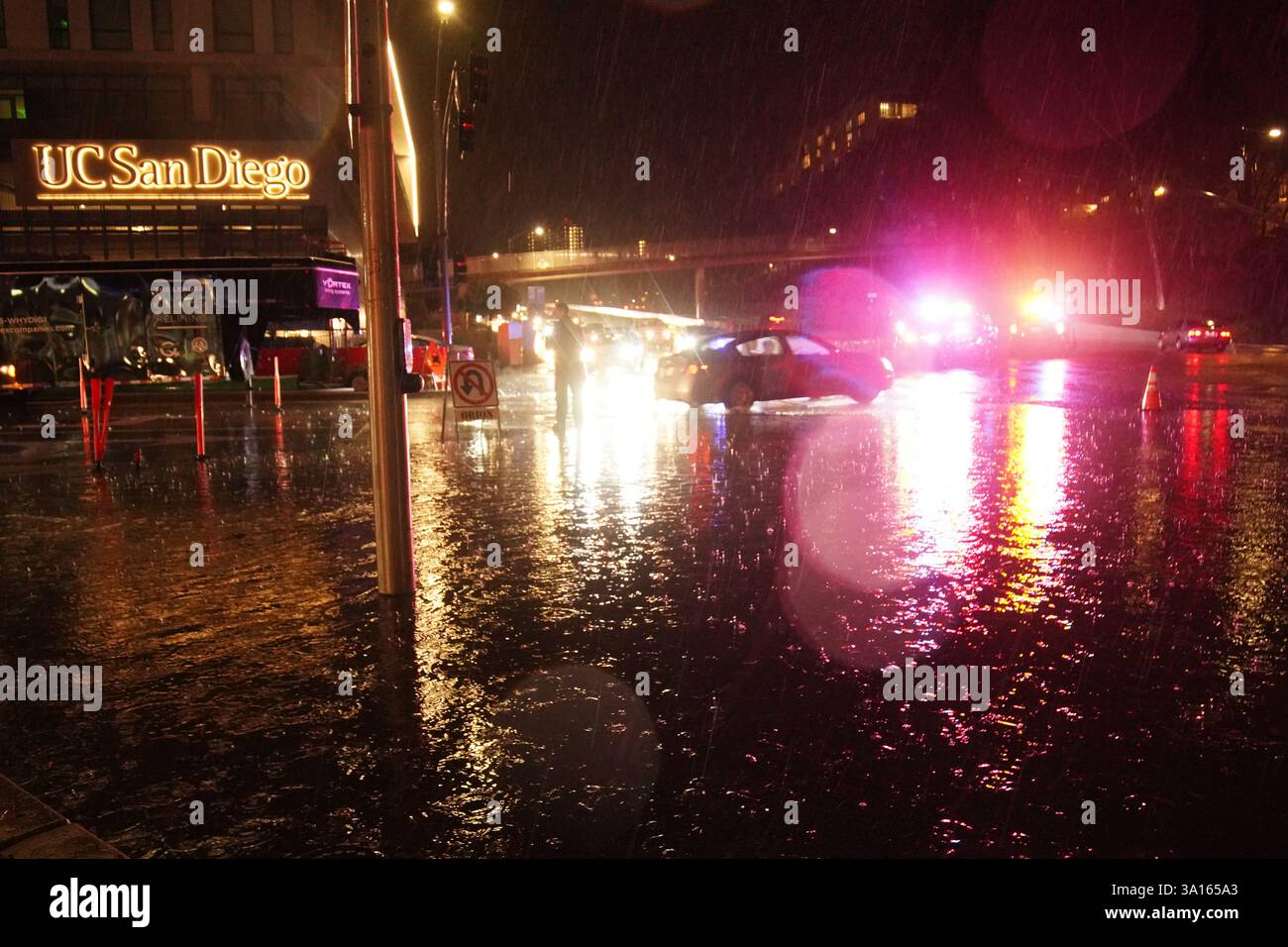 La polizia coordina il traffico in un tratto allagato della strada. San Diego ha subito una forte pioggia che ha portato a significative inondazioni in tutta la città. Nell'area di la Jolla, almeno quattro auto sono sommerse con livelli d'acqua quasi interamente coperti. Contemporaneamente, diversi incidenti automobilistici si sono verificati durante la tempesta, provocando risposte dal dipartimento di polizia di San Diego. Le autorità hanno chiuso le strade allagate per garantire la sicurezza pubblica, mentre il National Weather Service ha emesso un avviso di inondazione per alcune zone di San Diego. Foto Stock