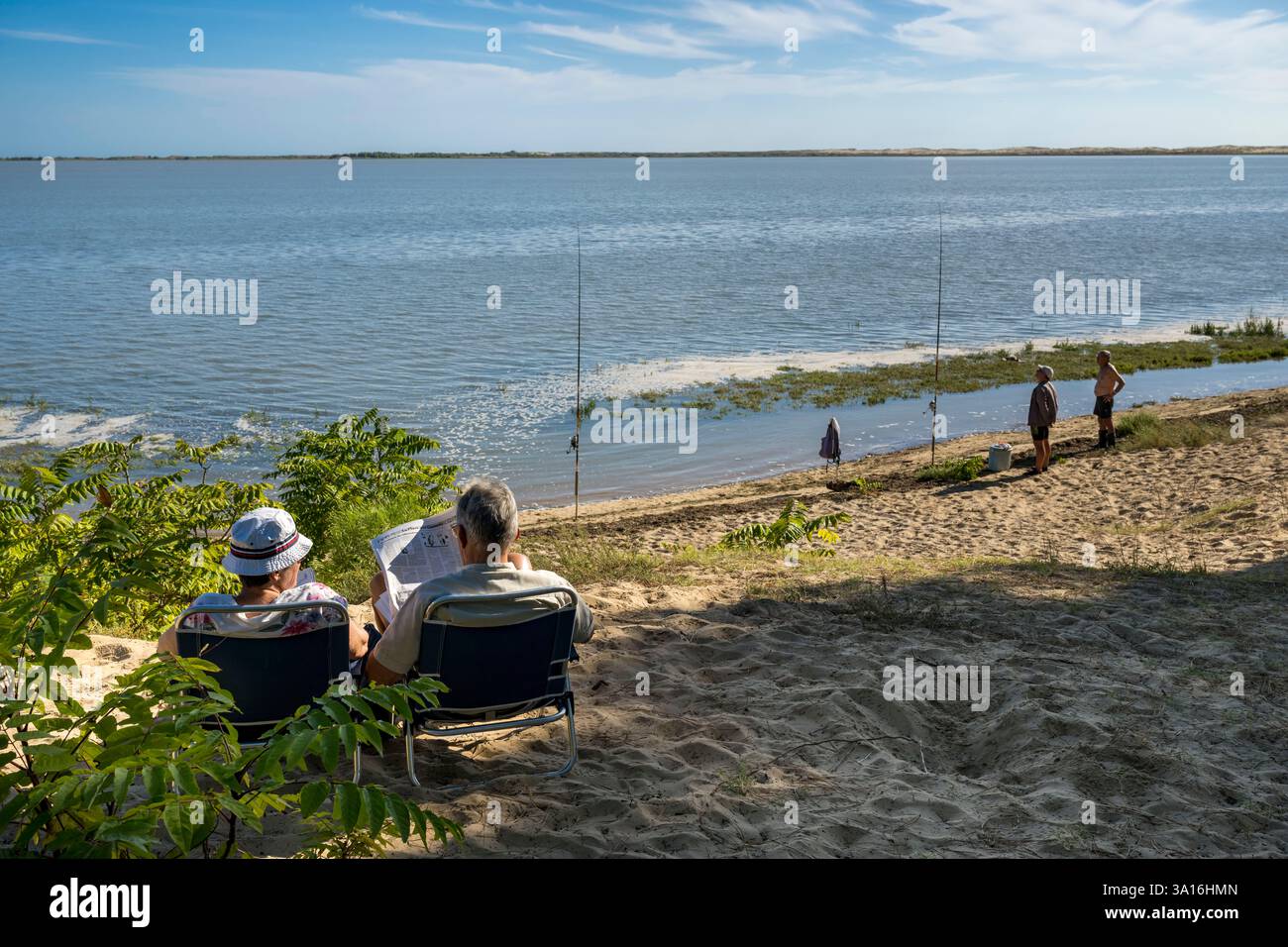 Francia, Charente-Maritime, Royan, Les Mathes, pescatori ai margini della baia di Bonne Anse in alta marea e leggendo il giornale Foto Stock