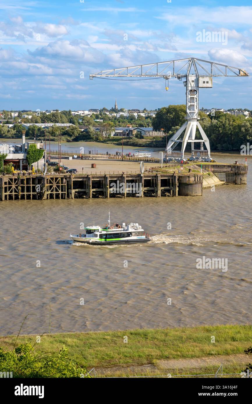 Francia, Loira Atlantica, Nantes, Ile de Nantes, il Navibus che passa davanti al Banana Hangar sulle rive della Loira, la Titan Crane grigia sullo sfondo, vista dalle alture di Chantenay Foto Stock