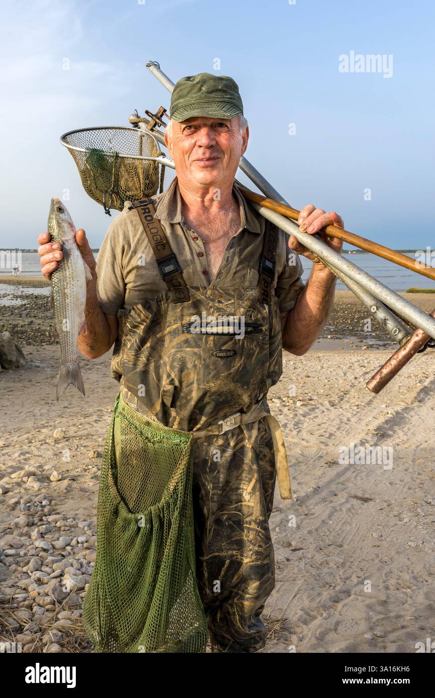 Francia, Charente Maritime, Port-des-Barques, pescatore di reti a mano Daniel Dupuis che ha catturato una triglia (pesce) Foto Stock