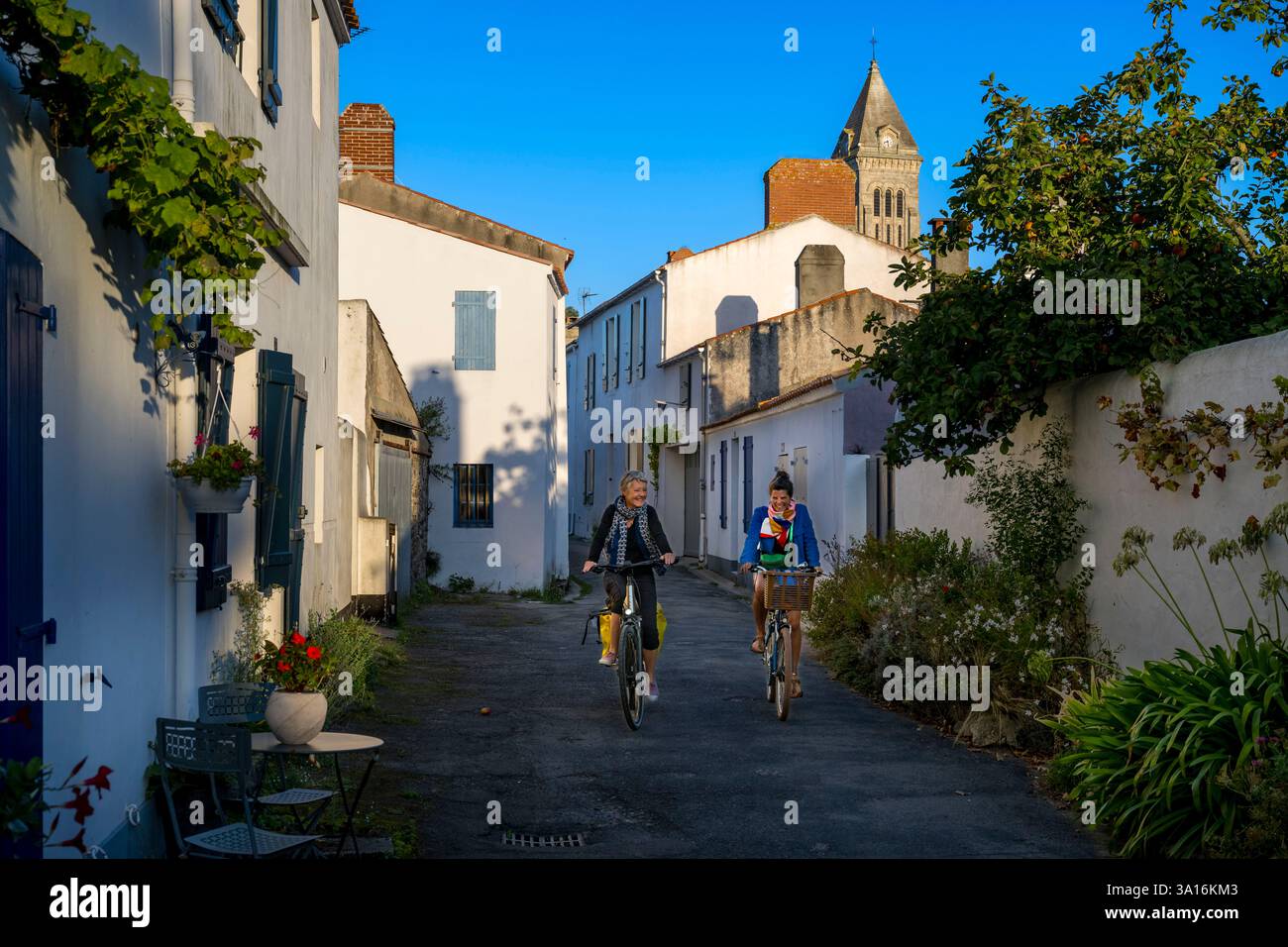 Francia, Vandea, isola di Noirmoutier, Noirmoutier en l'Ile, ciclisti nelle stradine Foto Stock