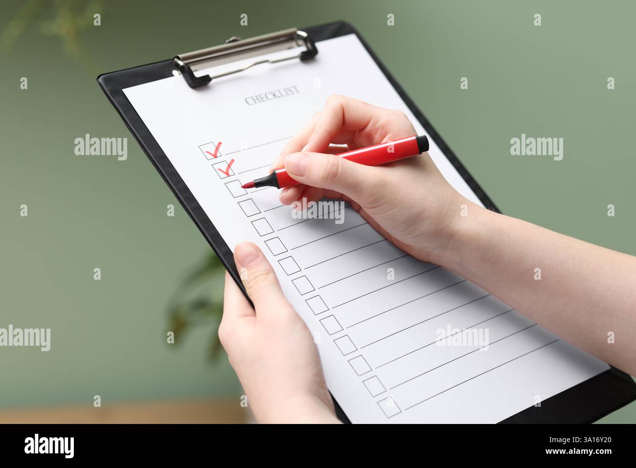 Donna che riempie la lista di controllo con un marcatore al chiuso, primo piano Foto Stock