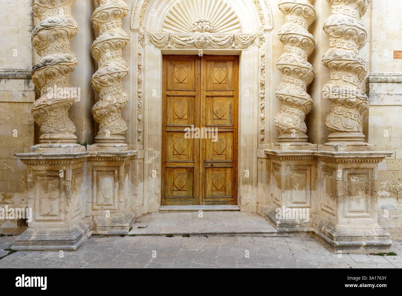 Italia, Sicilia, Val di noto, Palazzolo Acreide, città tardo barocca dichiarata Patrimonio dell'Umanità dall'UNESCO, chiesa dell'Annunziata distrutta dal grande terremoto del 1693 ricostruita in stile barocco nel XVIII secolo, facciata progettata da Giuseppe Ferrara, facciata con decorazioni di uva, principi e fichi, scultura di un angelo sopra la porta e colonne contorte Foto Stock