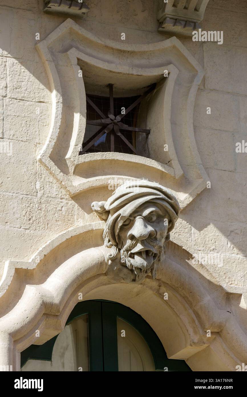 Italia, Sicilia, Ragusa, città dichiarata Patrimonio dell'Umanità dall'UNESCO, dettaglio della facciata del Palazzo Bertini costruito in stile barocco nel XVIII secolo a Ragusa superiore (alta Ragusa) situato in corso Italia, uno dei tre volti ridicoli della facciata tipica dello stile barocco che rappresenta il mendicante Foto Stock